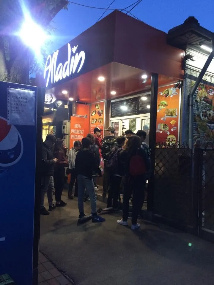 Clienți așteptând seara la geamul shaormeriei Alladin din Buzău