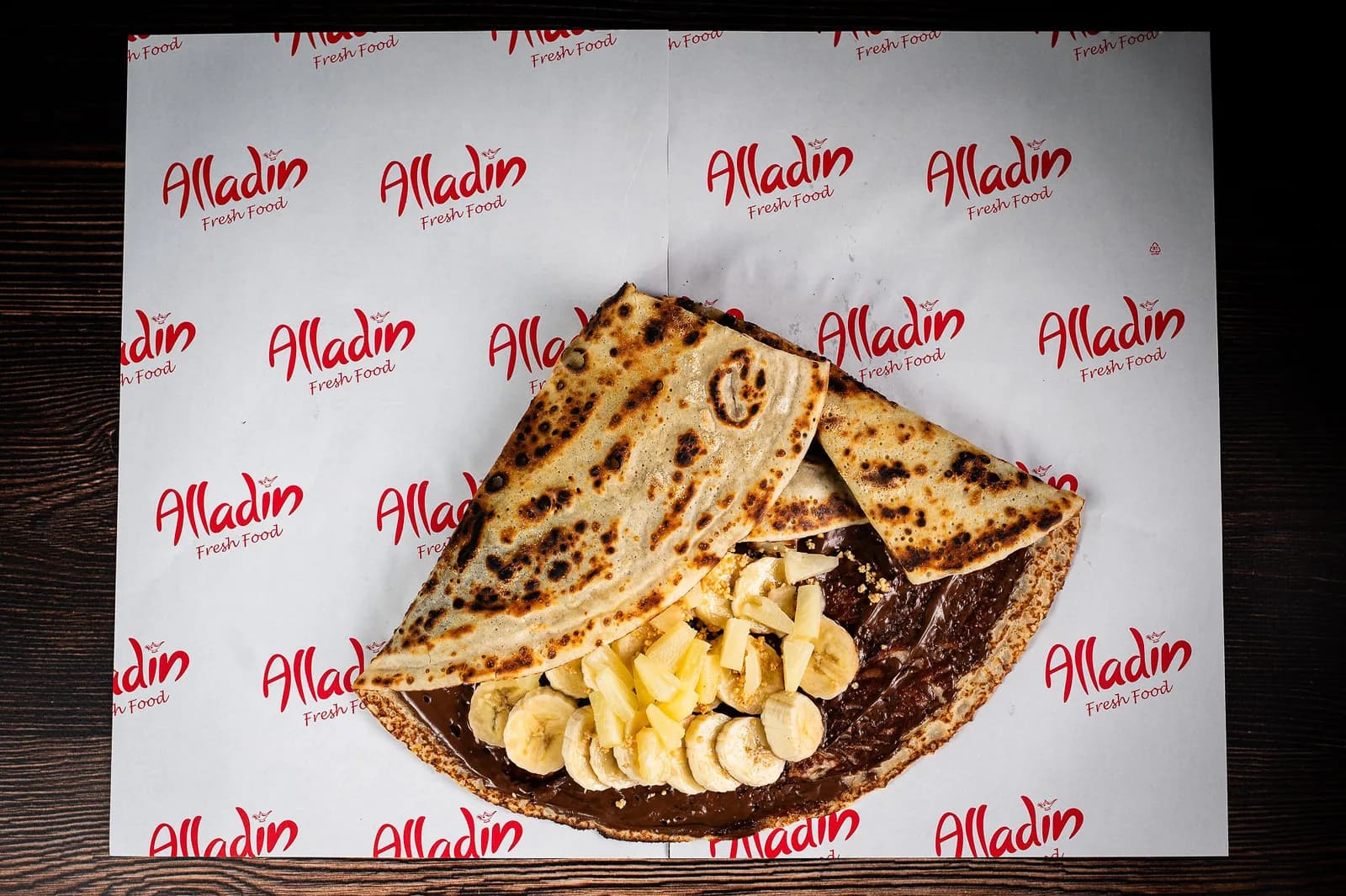 Clătită Fresh împăturită peste Nutella, banane și ananas, pe hârtia Alladin