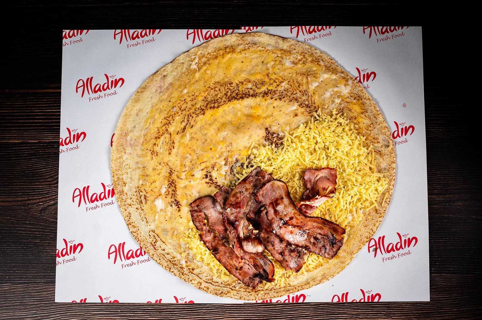 Clătită sărată Bacon desfăcută: cașcaval ras, ouă și bacon, pe hârtia brandată Alladin