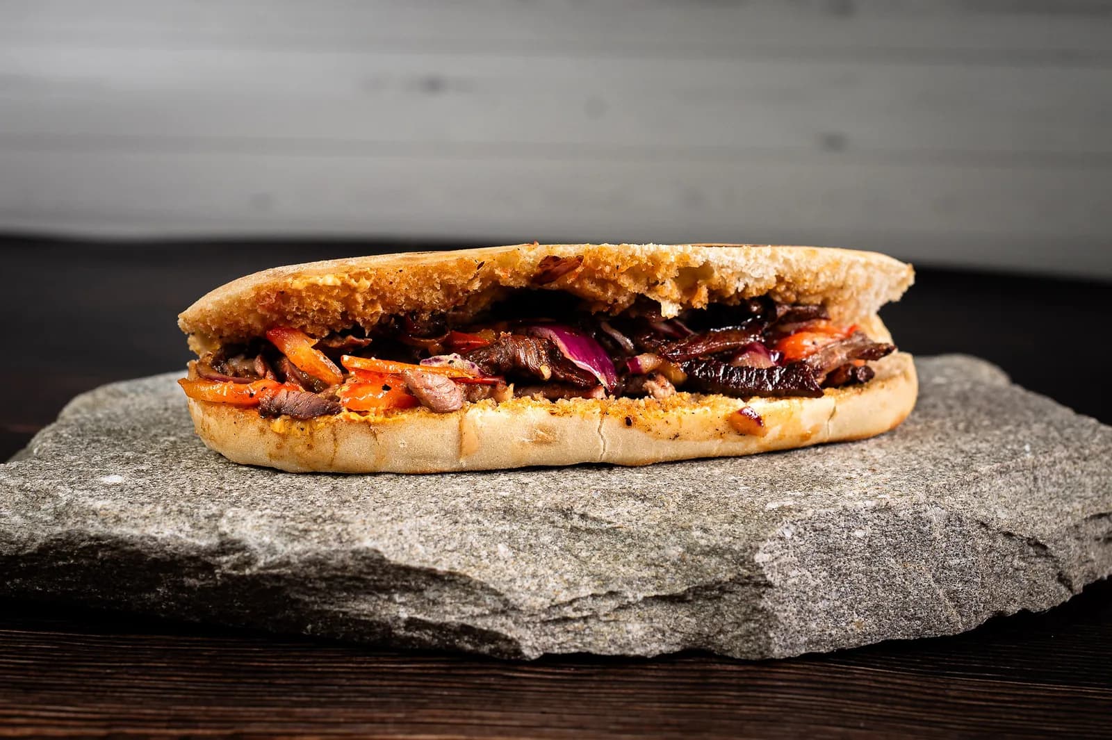 Baghetă Rustic cu pastramă de oaie și ardei, fotografiată pe fundal gri deschis